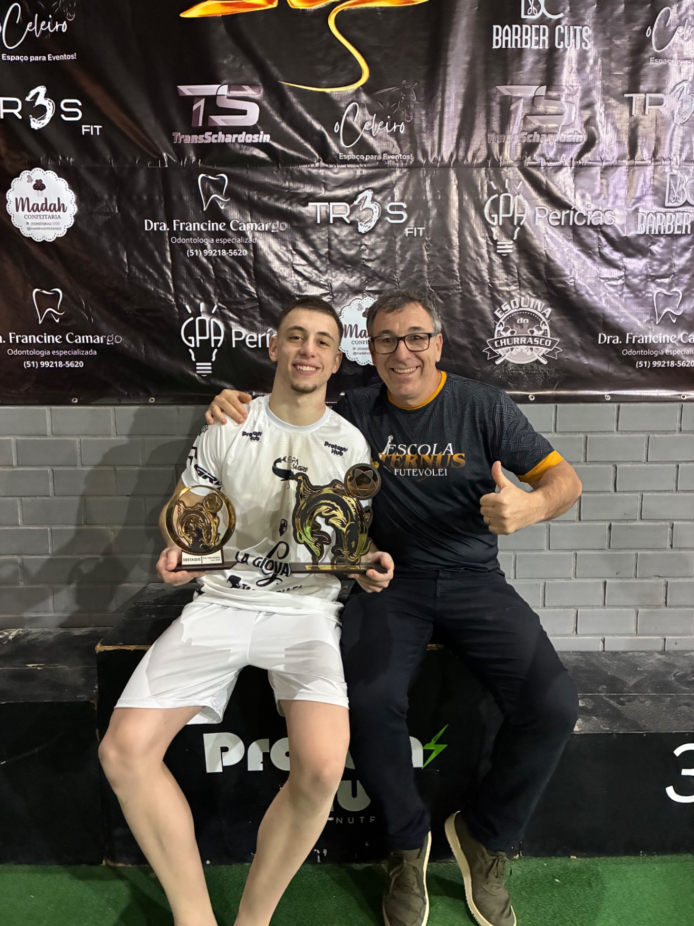 Aluno e professor com troféu de campeonato